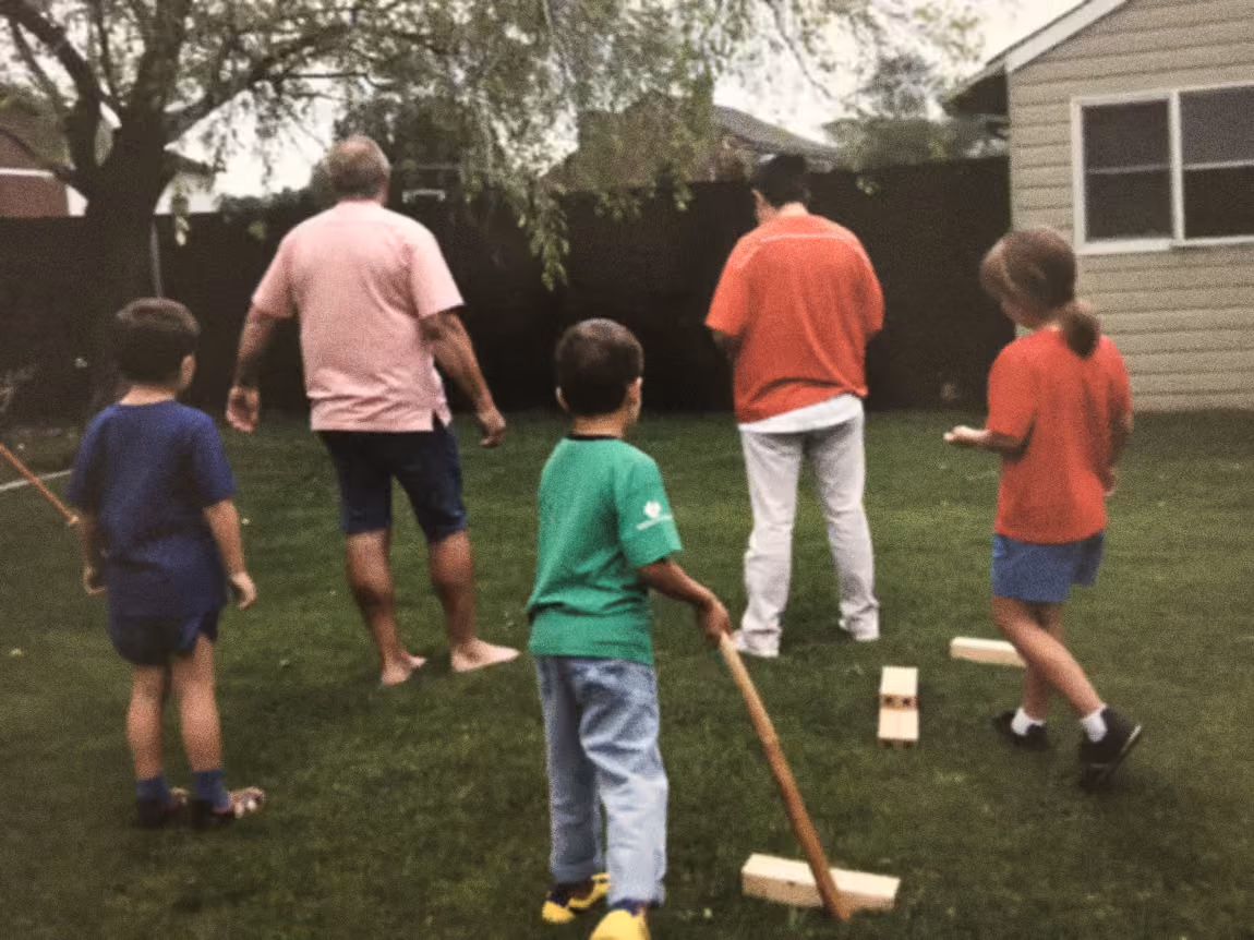 Drie generaties spelen een spel op het gras in de tuin