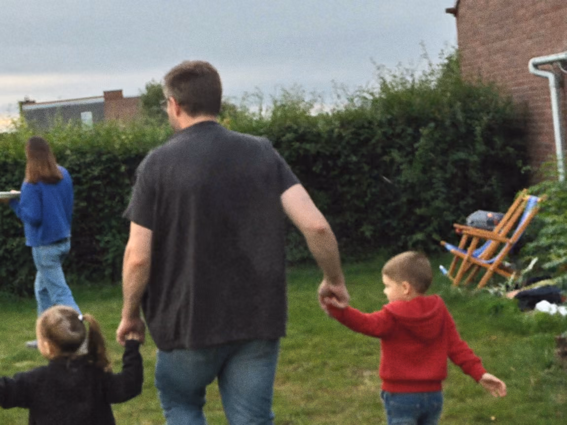 Vader loopt met twee kinderen over het gras tijdens een familiedag