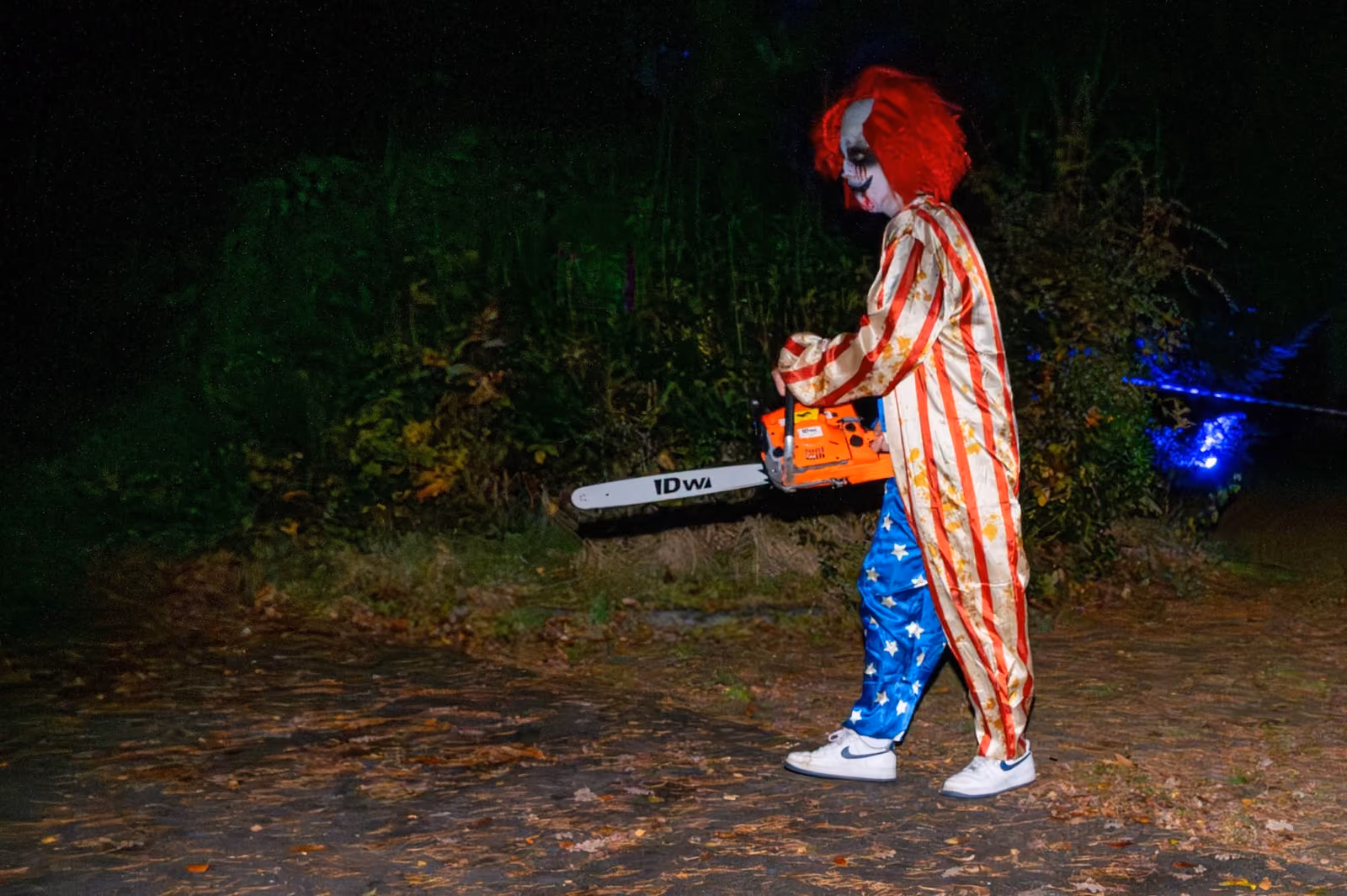 Scare actor als clown met kettingzaag langs de route