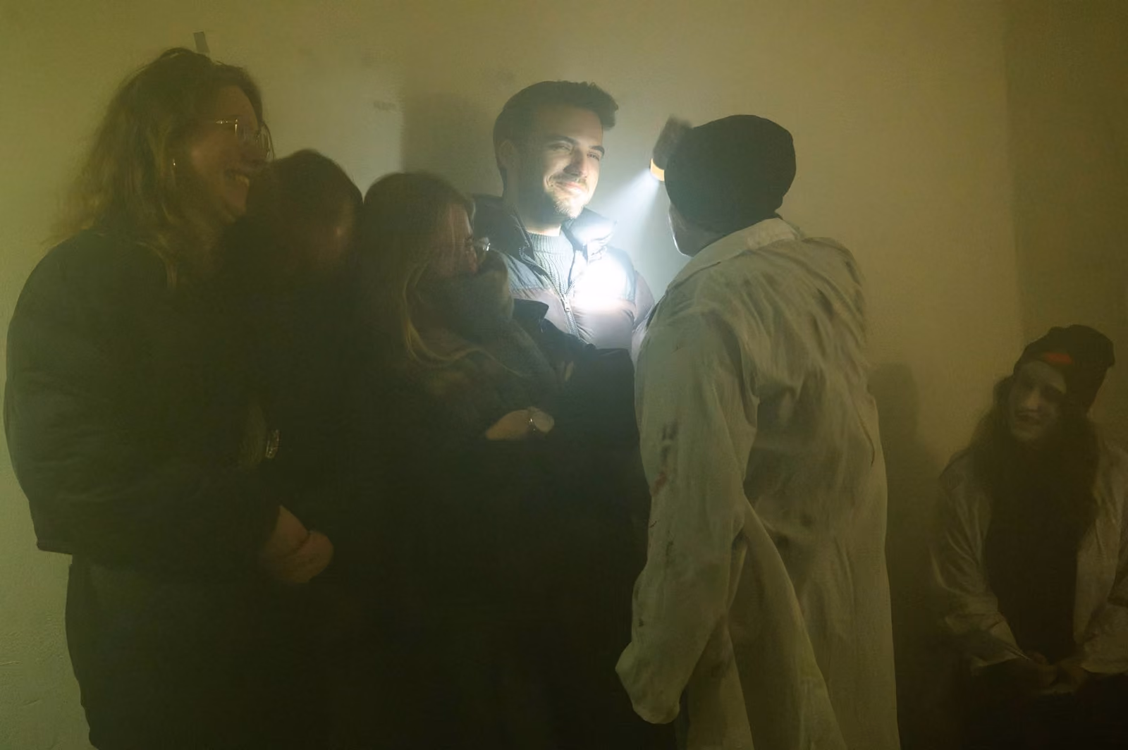Bezoekers met een zaklamp in een mistige ruimte tijdens de tocht